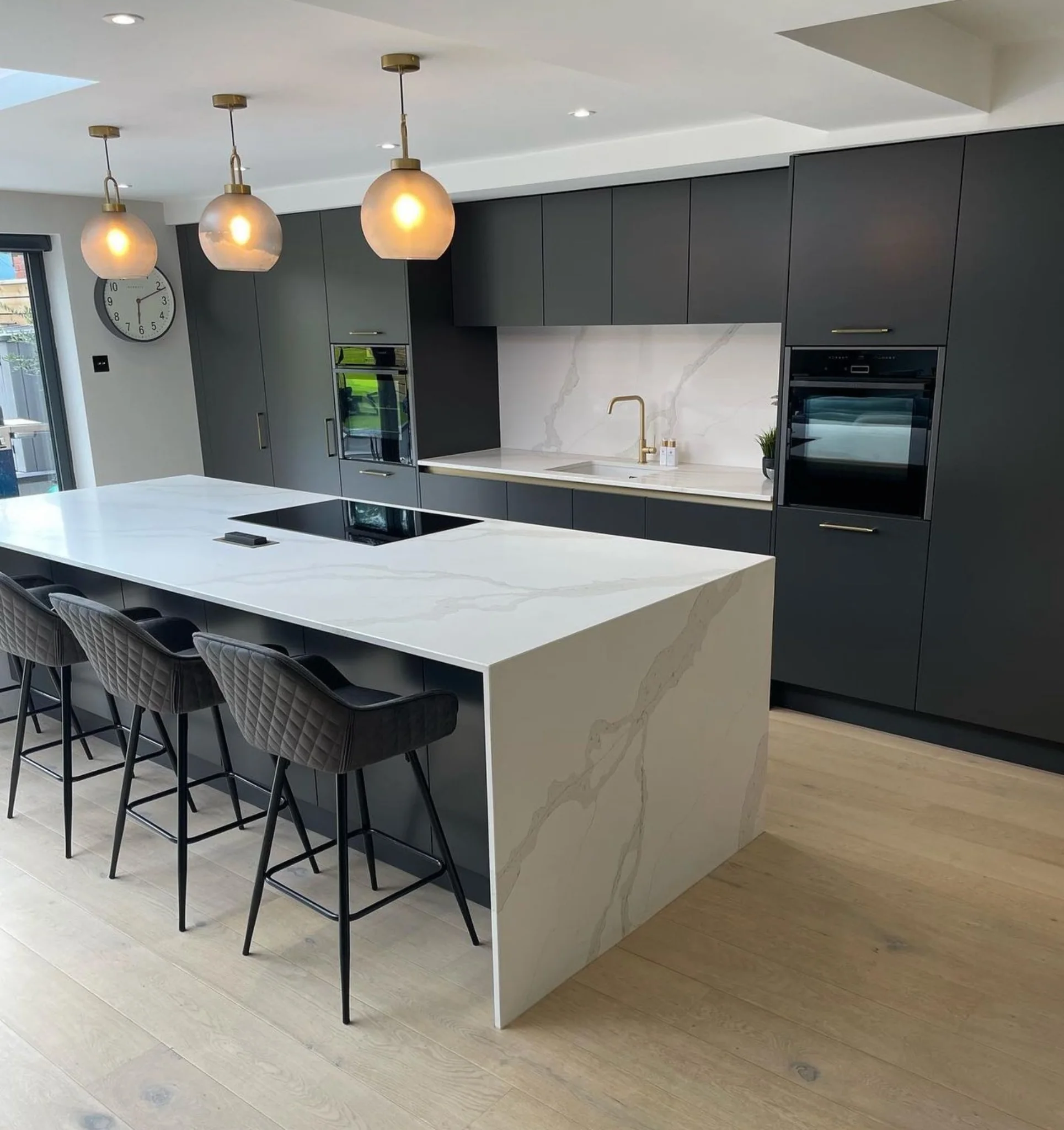 Veined quartz waterfall island & matching splashback for kitchen design inspiration.